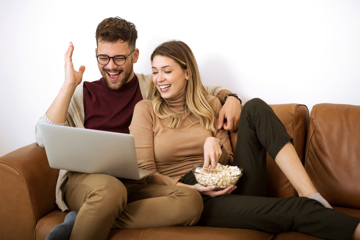 Young couple watching movie at home on laptop