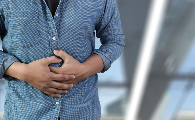 Midsection Of Man Touching Abdomen While Standing Against White Background