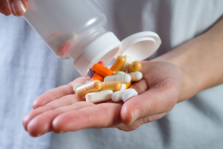 White and colored capsules and tablets in the hand of a girl or woman. Taking vitamins, painkillers, medications, food additives. The concept of prevention and treatment of diseases, health care and medicine. Pregnancy planning, filling in deficits.