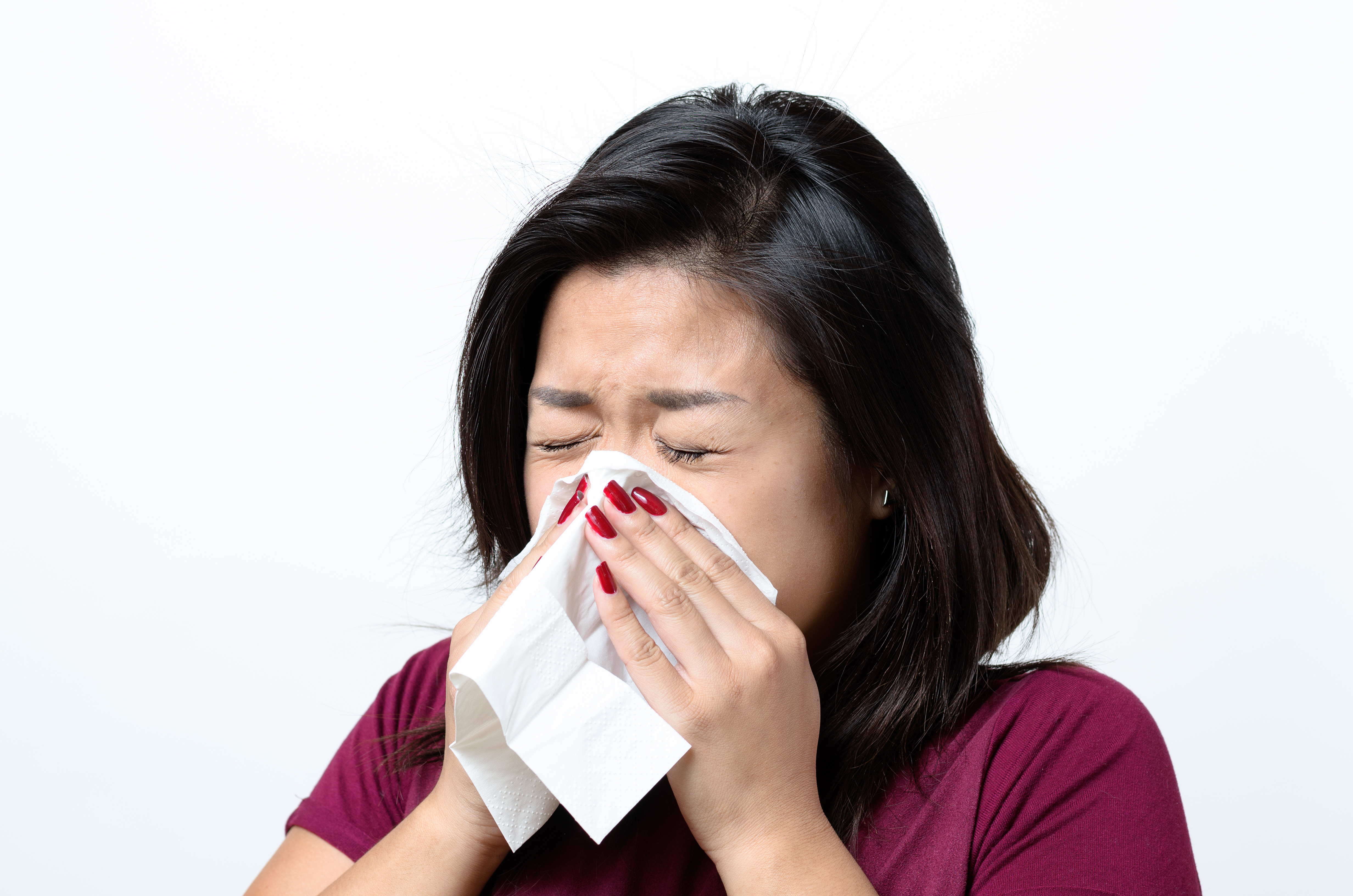 Young Woman Sneezing Against White Background