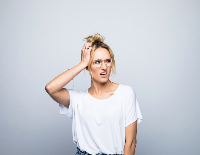Confused woman looking away while scratching head