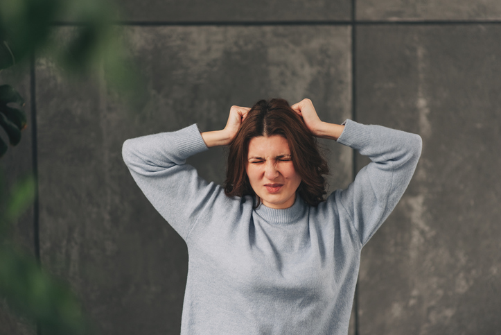 A very frustrated and angry woman pulling her hair. Isolated on white.
