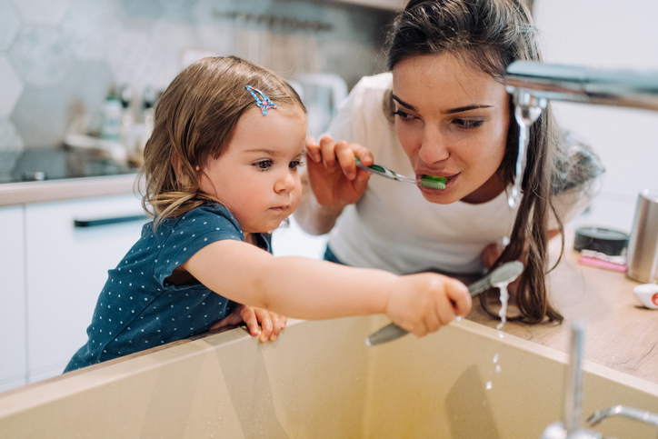 Mother and daughter brushing teeth together.
