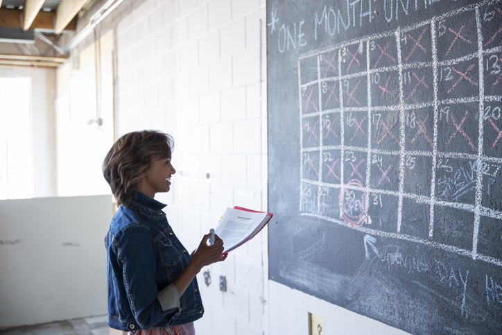 Female entrepreneur looking at blackboard calendar in office