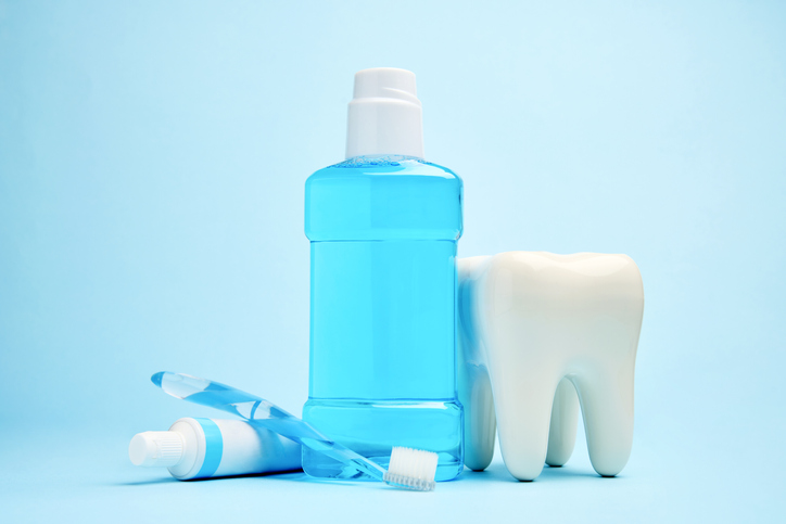 A toothbrush with toothpaste and mouthwash on blue background