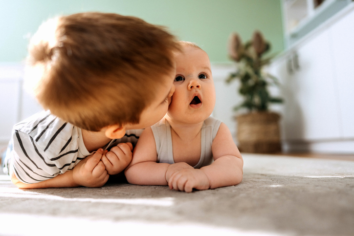 Portrait of two cute little brothers bonding while laying on a floor at home