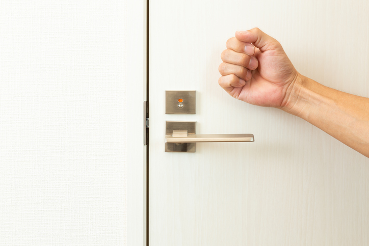 A man's hand knocks on the toilet door.