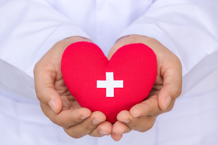 Close-Up Of Doctor Holding Heart Shape With Red Cross