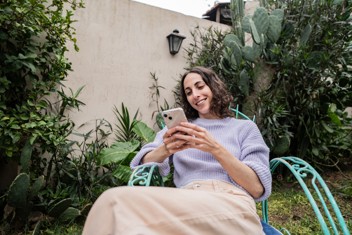 Young woman typing on mobile phone in the backyard