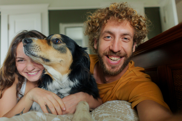 Selfie of cheerful man and woman with dog at home