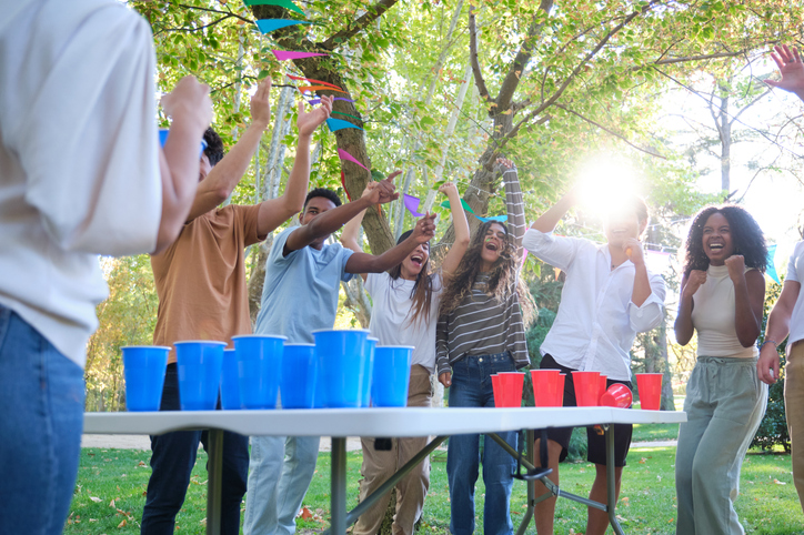 Group of friends celebrating winning a beer pong game in the park