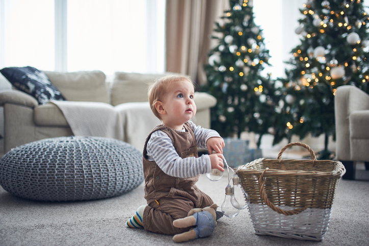 Child playing with a basket of ornaments in a cozy living room decorated for the holidays