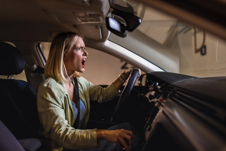 Young blonde woman driving in garage angry and stressed.