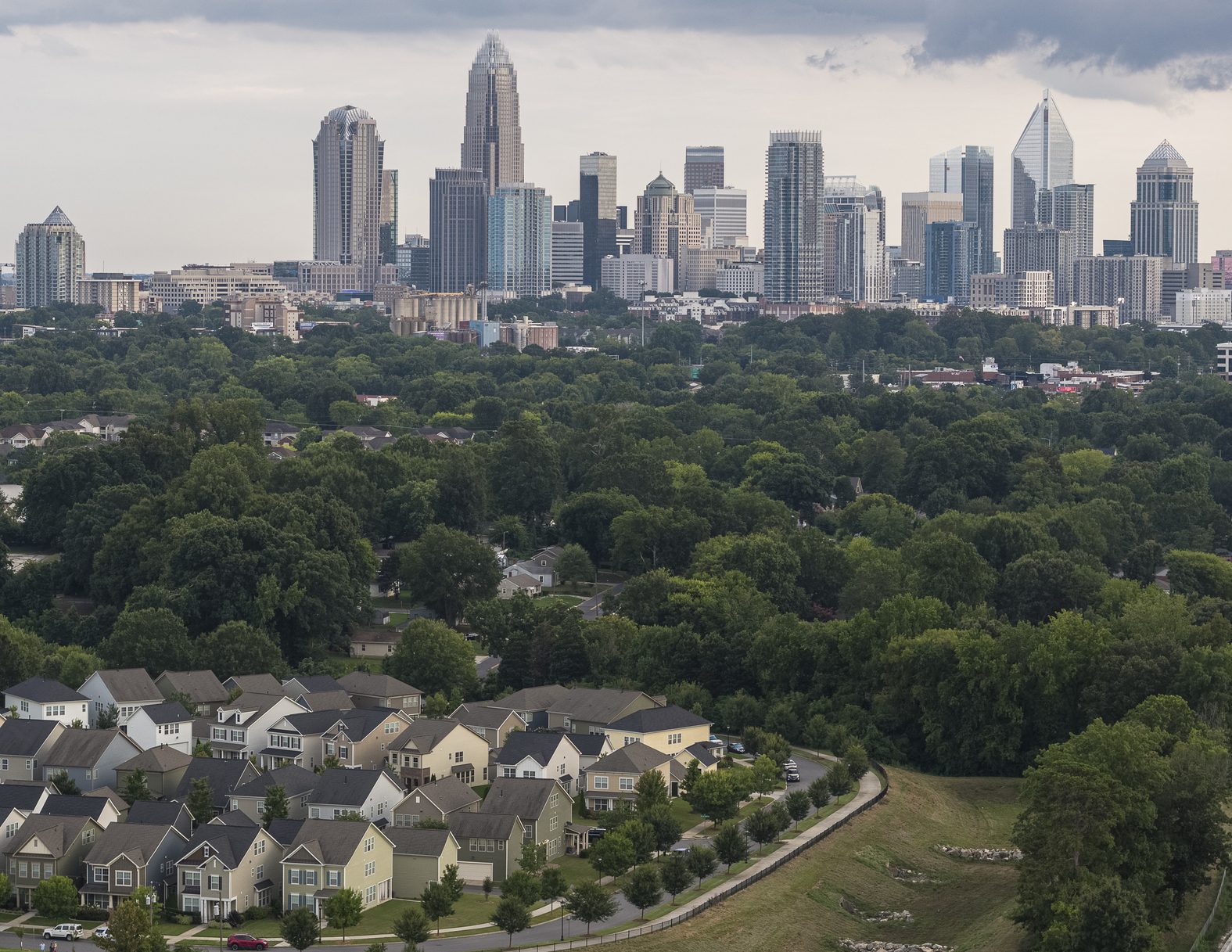 Residential houses with the distant view of Downtown Charlotte, North Carolina, USA, against the stormy sky in the evening. Stitched vertical panorama.