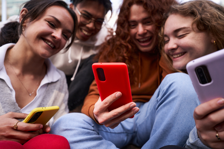 Group of friends gathering using smartphone all together watching videos on social media.