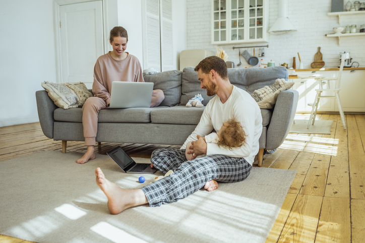 Smiling businesswoman and businessman with daughter working on laptop at home