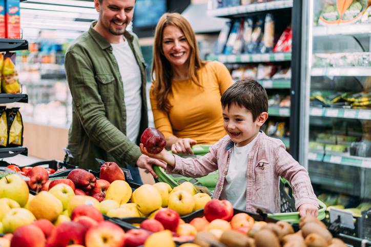 Smiling family with shopping cart choosing products in supermarket.