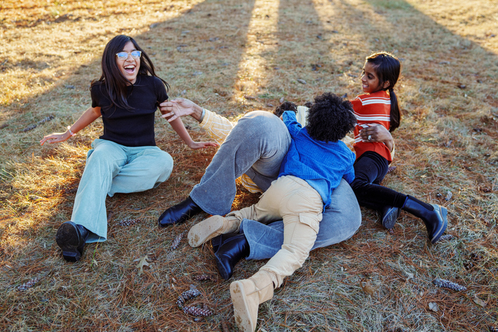 Playful group of girl cousins rough housing with their grandma outside