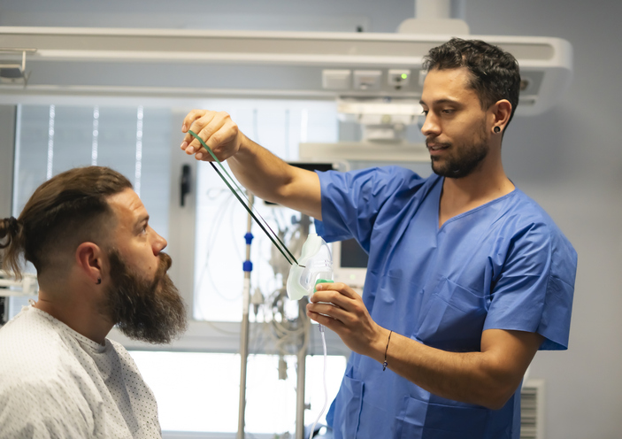 Nurse holding oxygen mask assisting patient in hospital room