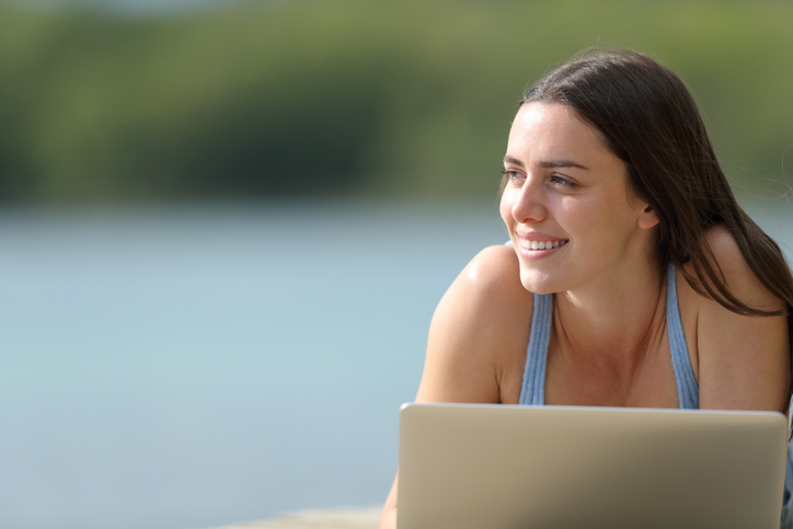 Happy woman with a laptop looks at side in nature