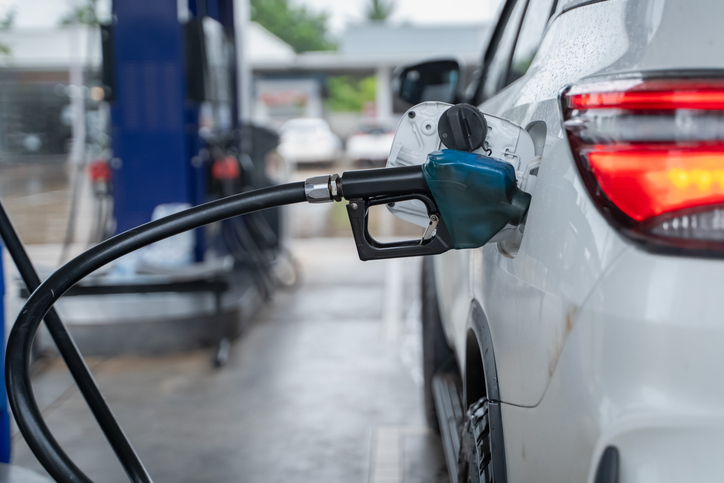 The fuel filler valve is inserted into the fuel filler neck. White car at gas station, transportation and industry concept.