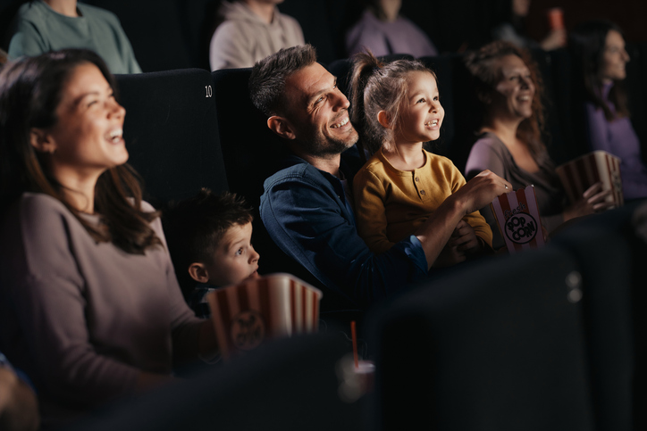 Cheerful family watching a funny movie in theatre.