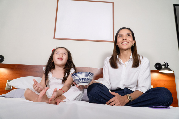 Mother and daughter eating popcorn watching tv in bed