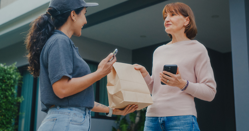 Senior Caucasian customer scanning phone to pay for takeaway food delivery at house. Contactless payment, courier service, online purchase or e commerce concept.