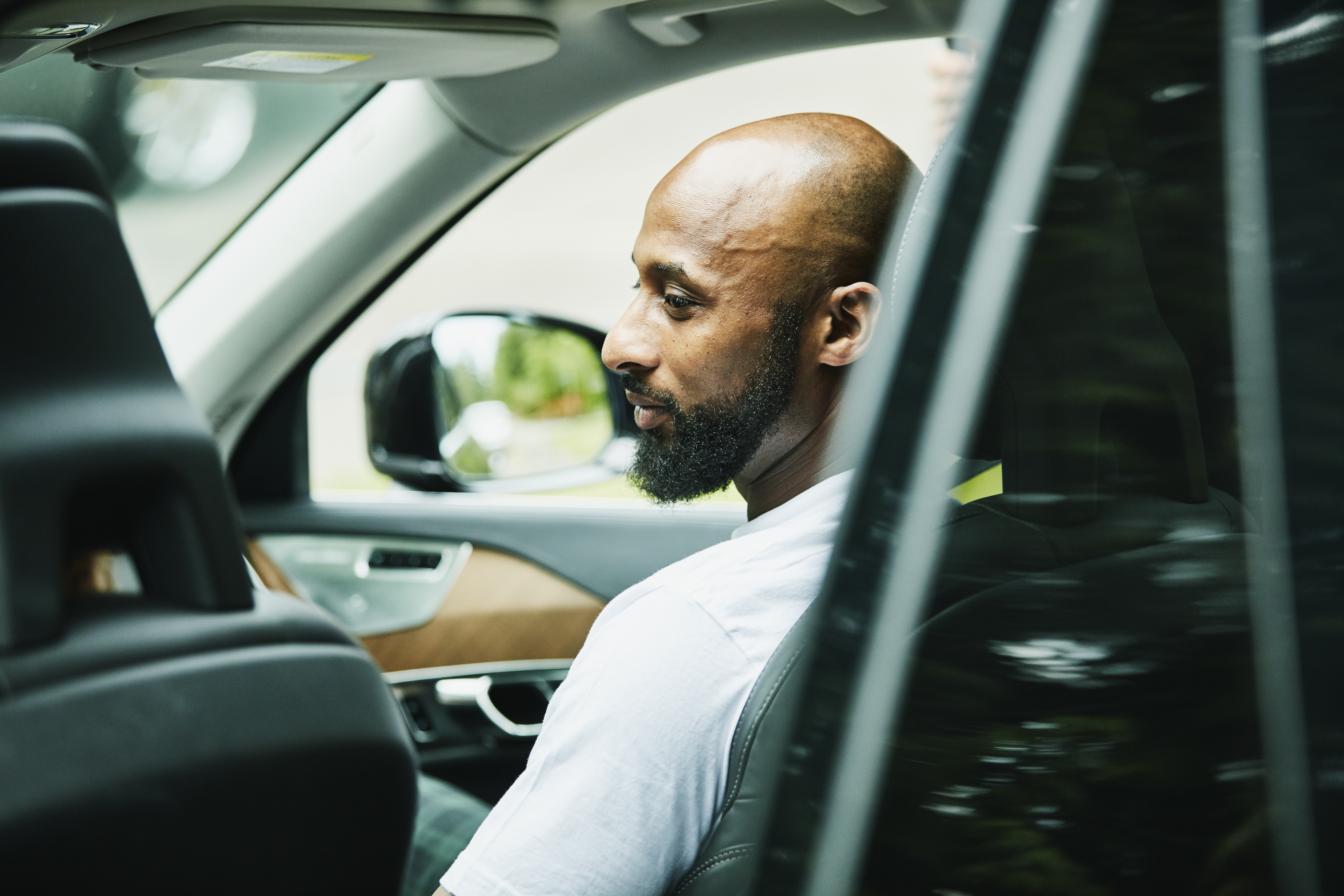 Smiling man seated in passenger seat of car waiting