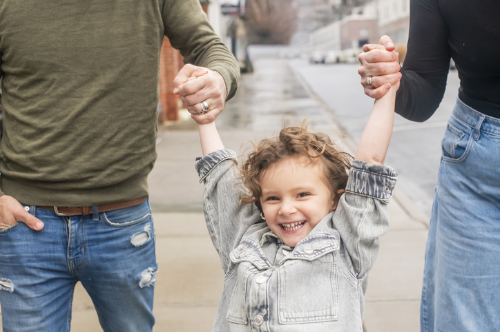 A child holds on with her parents