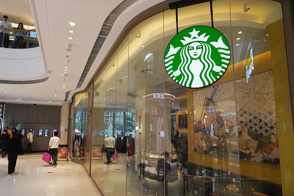 The Starbucks storefront with its iconic green logo is seen...