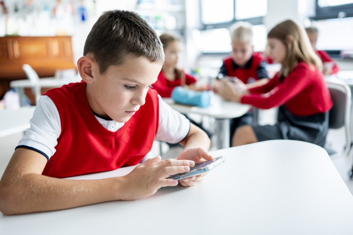 Boy using smartphone in classroom.