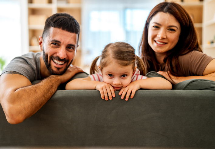 Happy family bonding at home peeking over sofa
